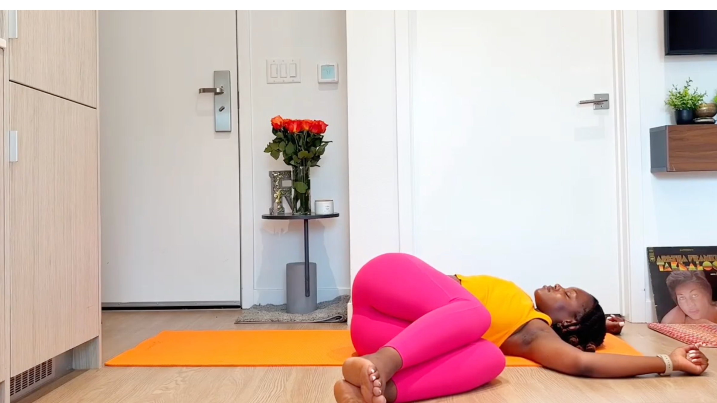 Yoga teacher practicing Supine Spinal Twist with Knees Bent.